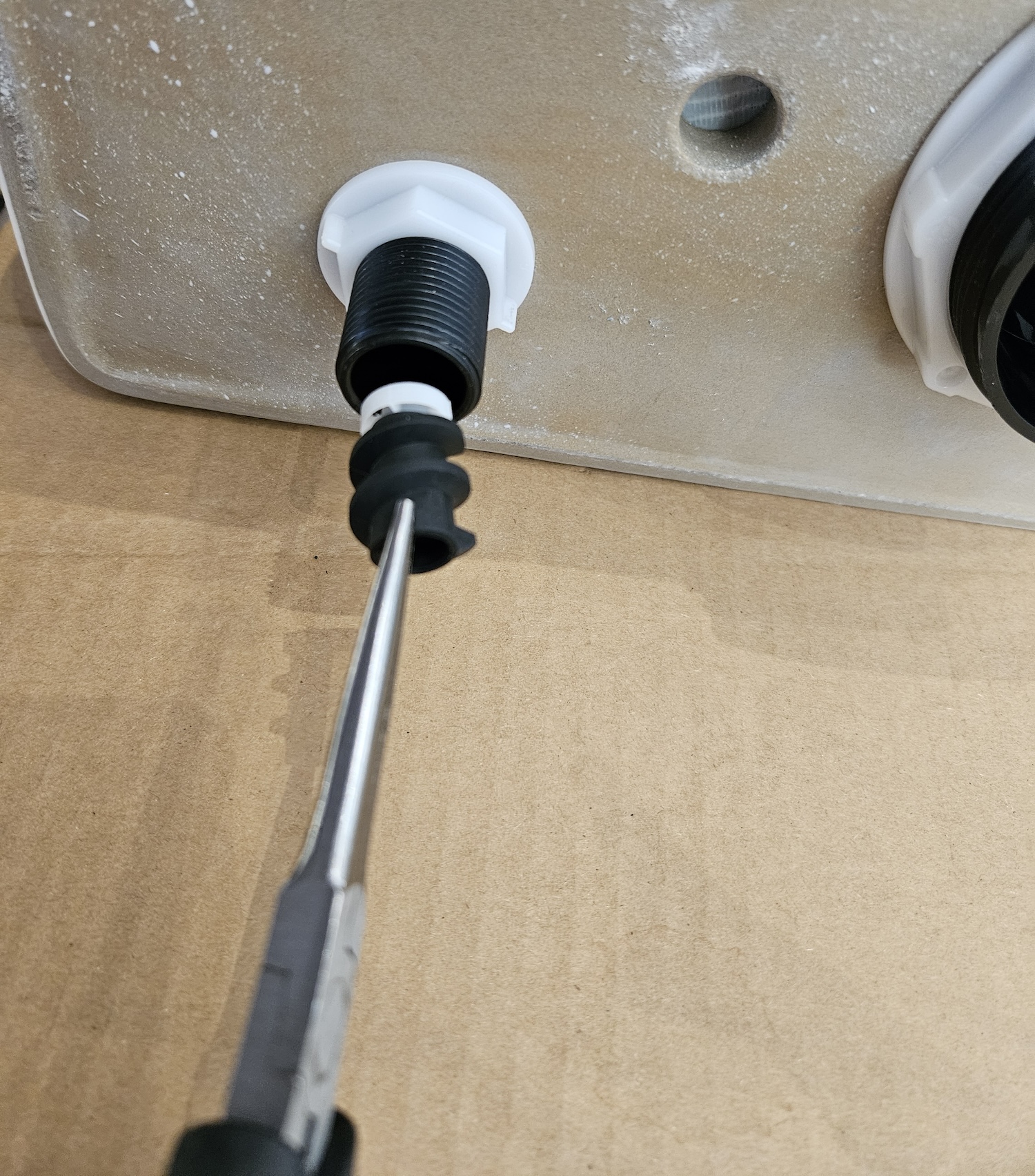 Me pulling out the flow regulator from our toilet tank using a pair of needle-nose pliers.